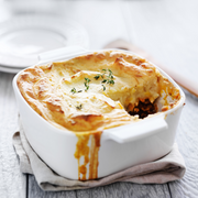 shepherds pie in a white glass container sitting on a grey table